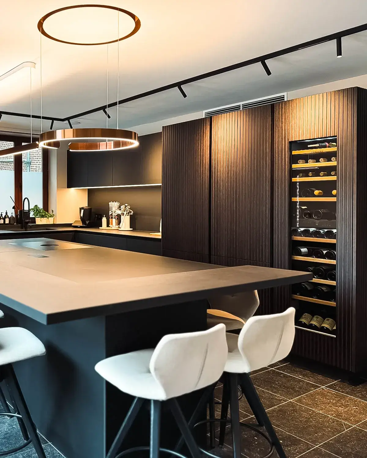 Cuisine moderne sur mesure avec grand îlot central, façades foncées en bois et cave à vin intégrée