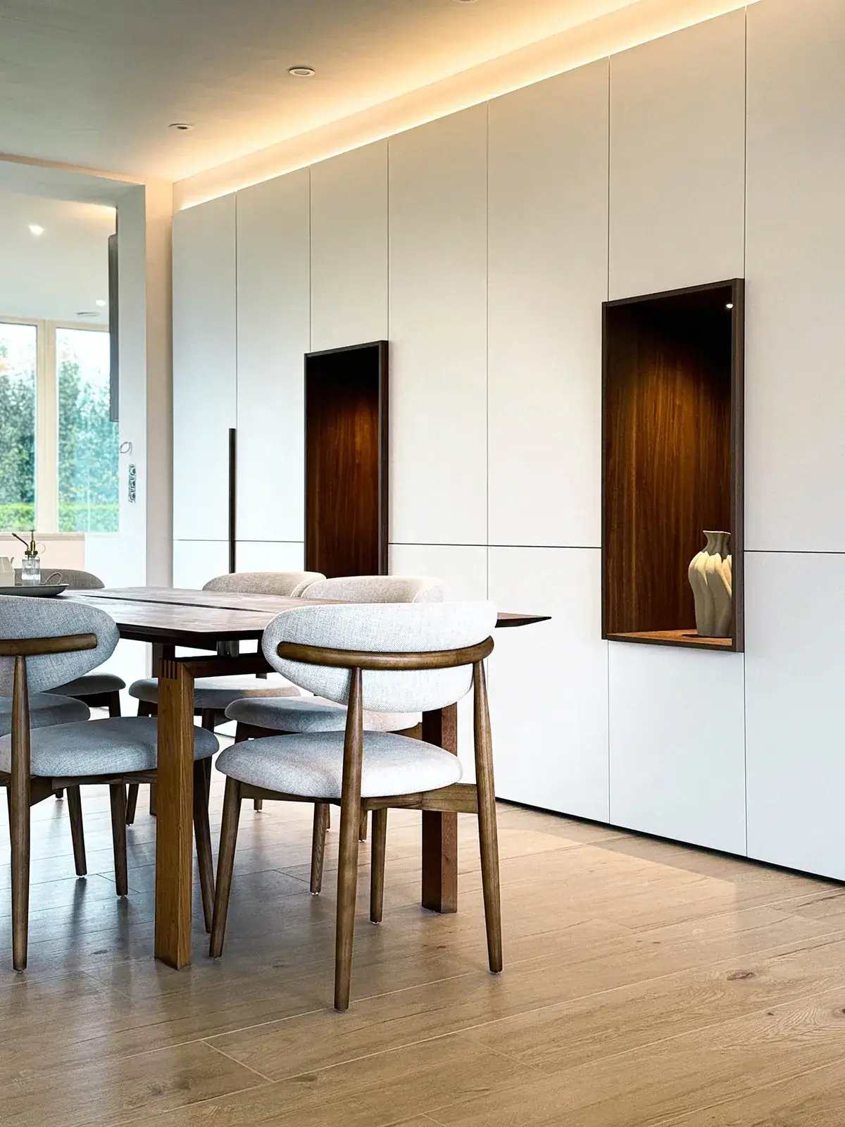 Placards sur mesure blancs toute hauteur avec niches décoratives en bois dans une salle à manger contemporaine