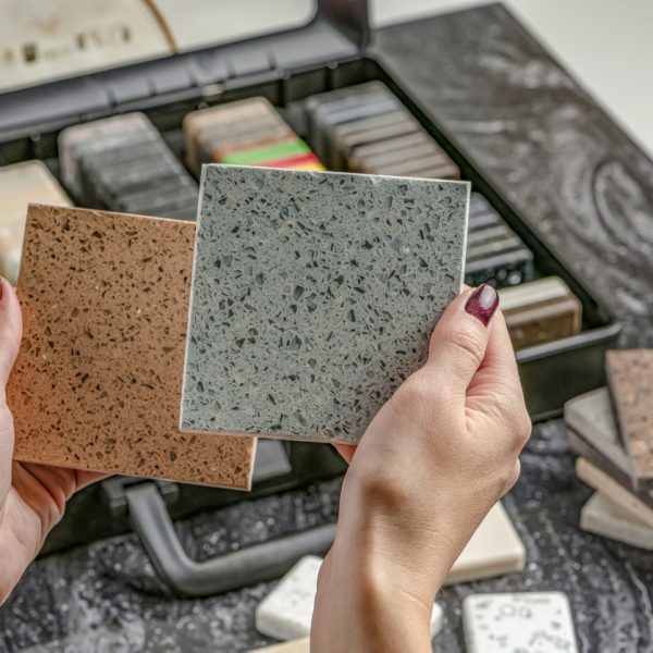 Samples of material for the countertop. Female hands are choosing interior elements for renovation. Samples of acrylic stone in hands Samples of material for the countertop. Female hands are choosing interior elements for renovation. Samples of acrylic stone in hands